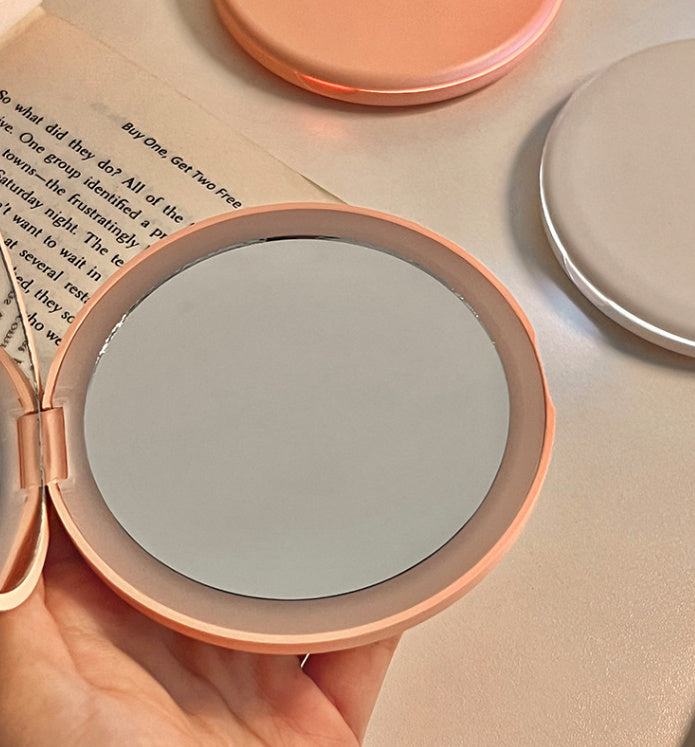 Espejo cosmético portátil con luz LED para maquillaje.