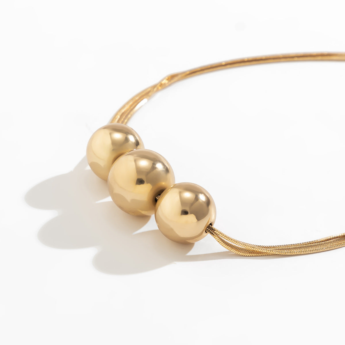 Collar multicapa con bola geométrica en dorado y plateado